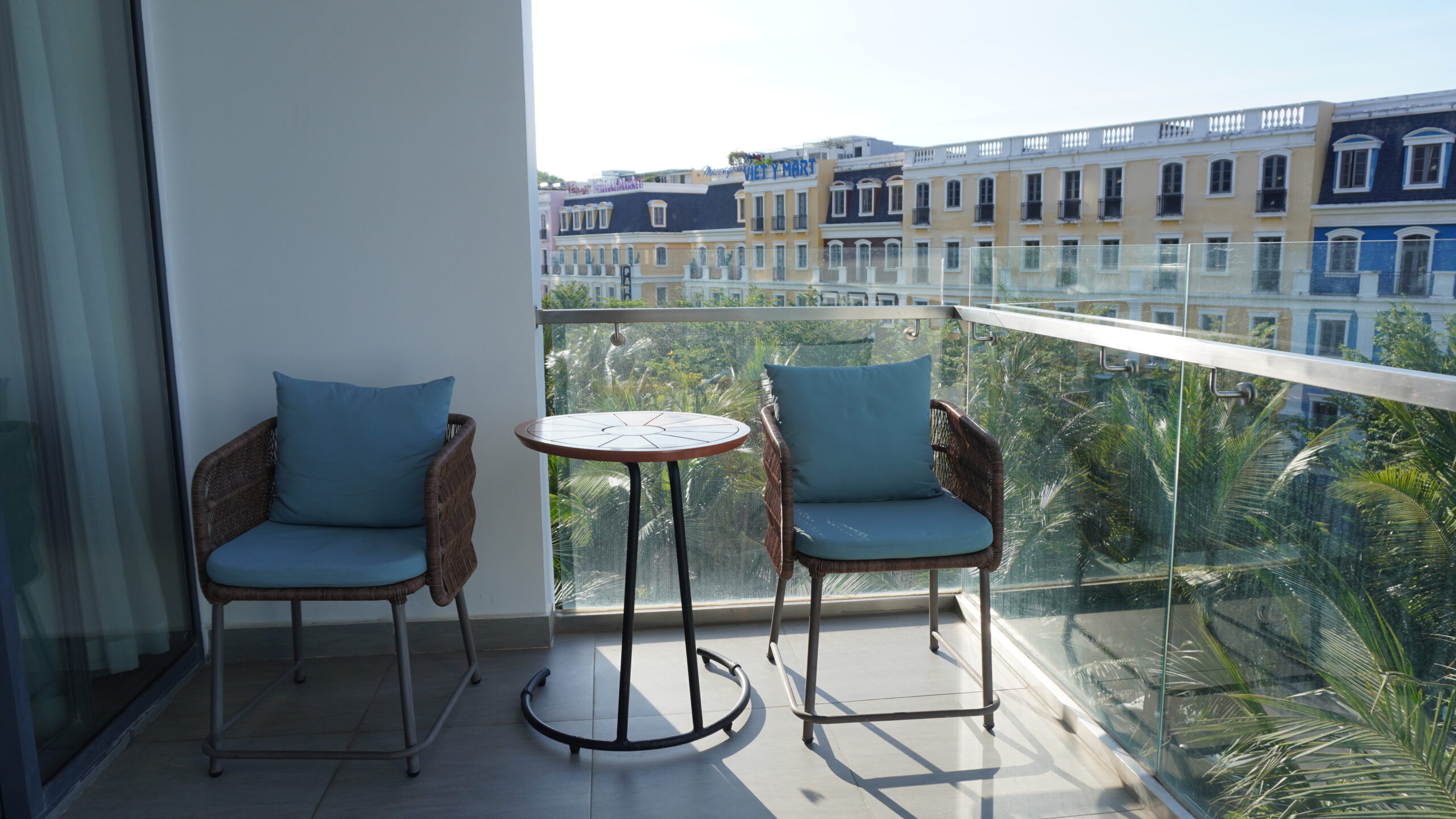 富國島翡翠灣高級公寓房型房間陽台一隅，兩張椅子與小圓桌對望著富國島街景與微光