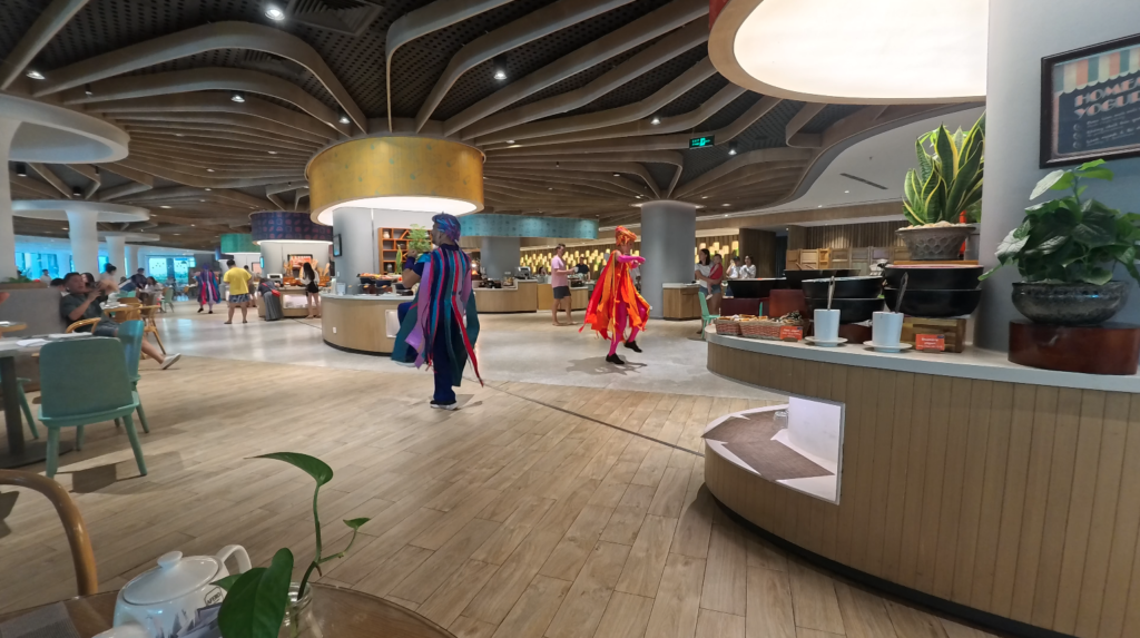 飯店大廳早晨表演時段,旅人穿梭其中,氛圍熱鬧歡樂