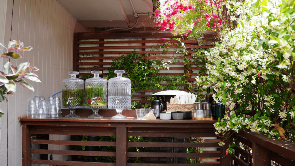 Il Giardino di Lilli 店內的自助飲水區：透明玻璃水壺中浸泡著新鮮切片水果與綠色香草，整齊排列的義大利優質橄欖油、海鹽與黑胡椒，採用深色玻璃瓶裝以保持新鮮度