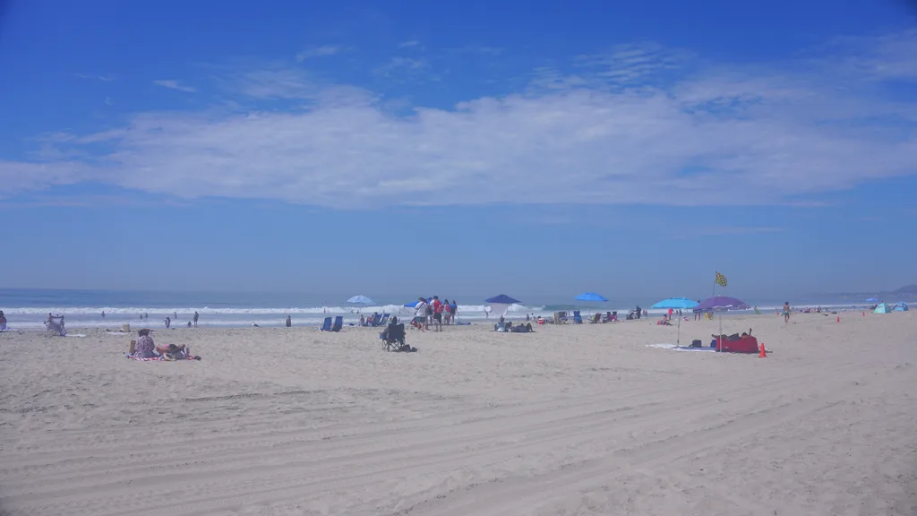 San Diego Mission Beach 真正的太平洋沙灘,可見海浪、多面陽傘與戶外活動的遊客 San Diego Mission Beach 真正的太平洋沙灘,可見海浪、多面陽傘與戶外活動的遊客