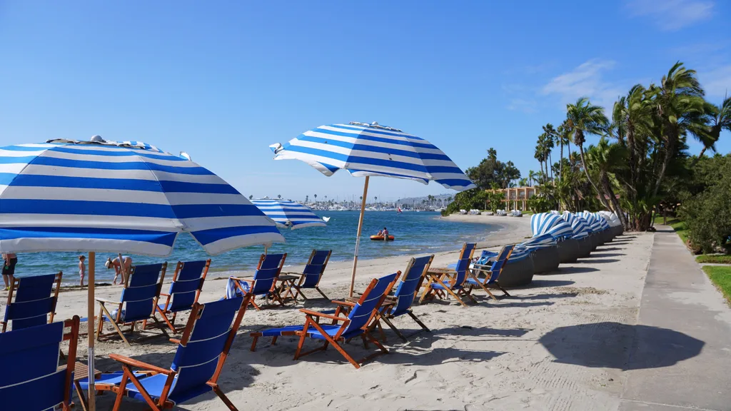 Bahia Resort Hotel 私人海灘,藍白條紋陽傘與藍色折疊躺椅沿岸排列,可見 Mission Bay 海灣與遊艇 Bahia Resort Hotel 私人海灘,藍白條紋陽傘與藍色折疊躺椅沿岸排列,可見 Mission Bay 海灣與遊艇