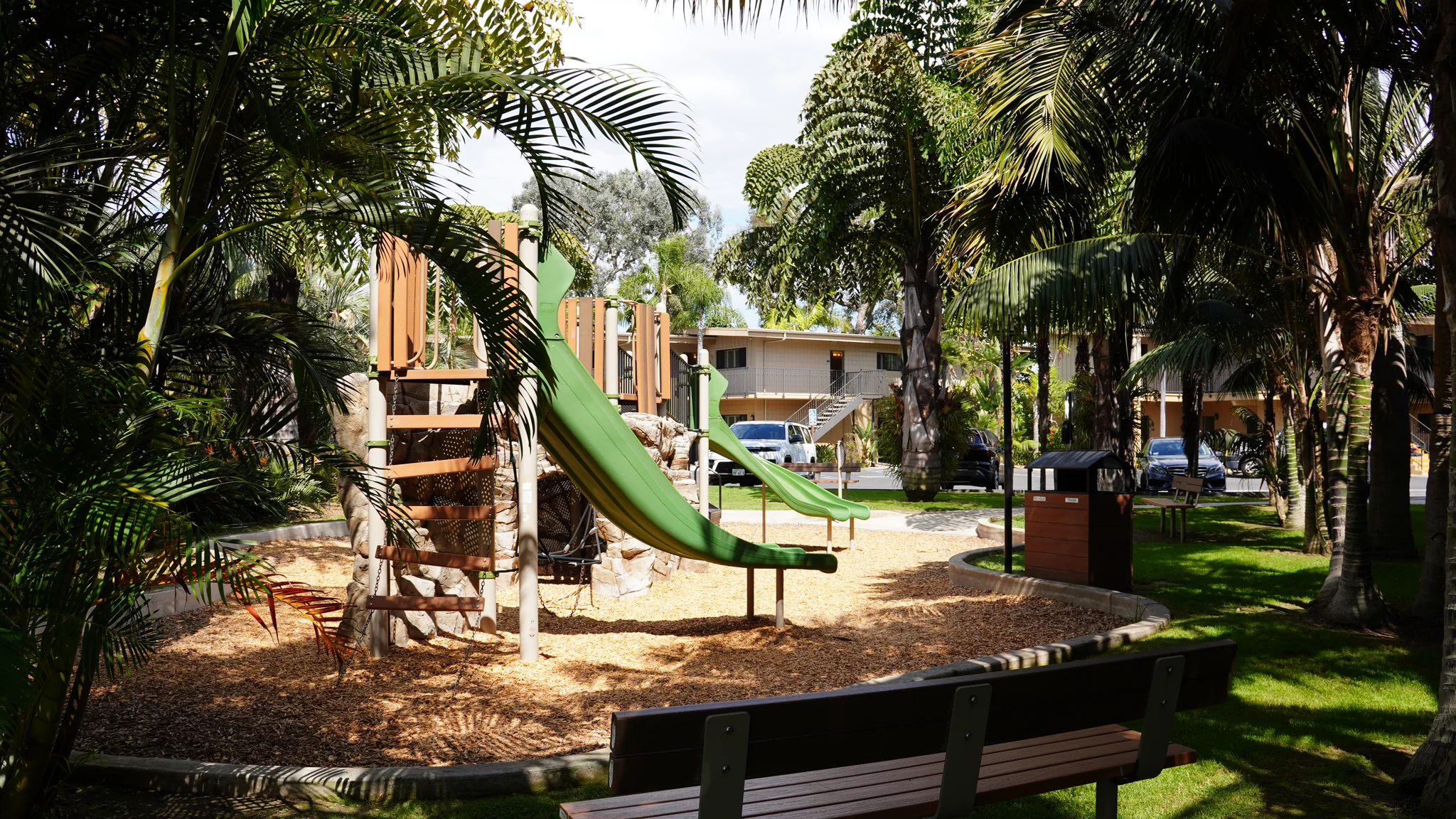 Bahia Resort Hotel Playground 兒童遊樂區，木頭與岩壁造型的遊樂設施搭配綠色溜滑梯，地上鋪木屑