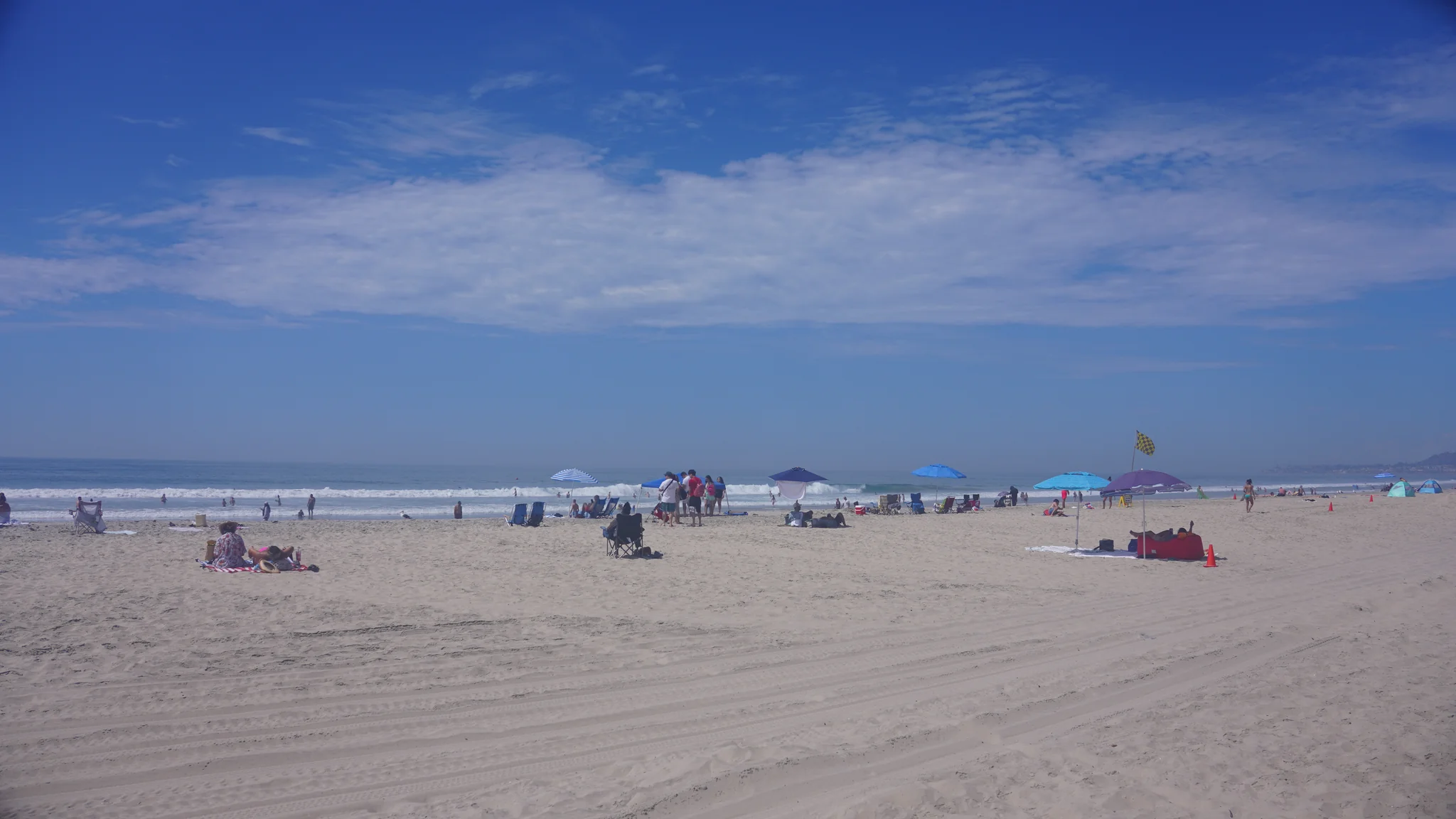Mission Beach 沙灘與海浪，藍天下散落著遮陽傘與遊客